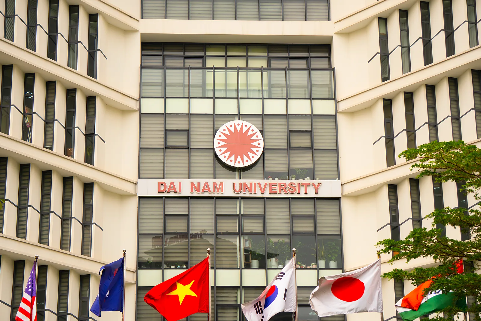 Dai Nam University main academic building facade with national flags